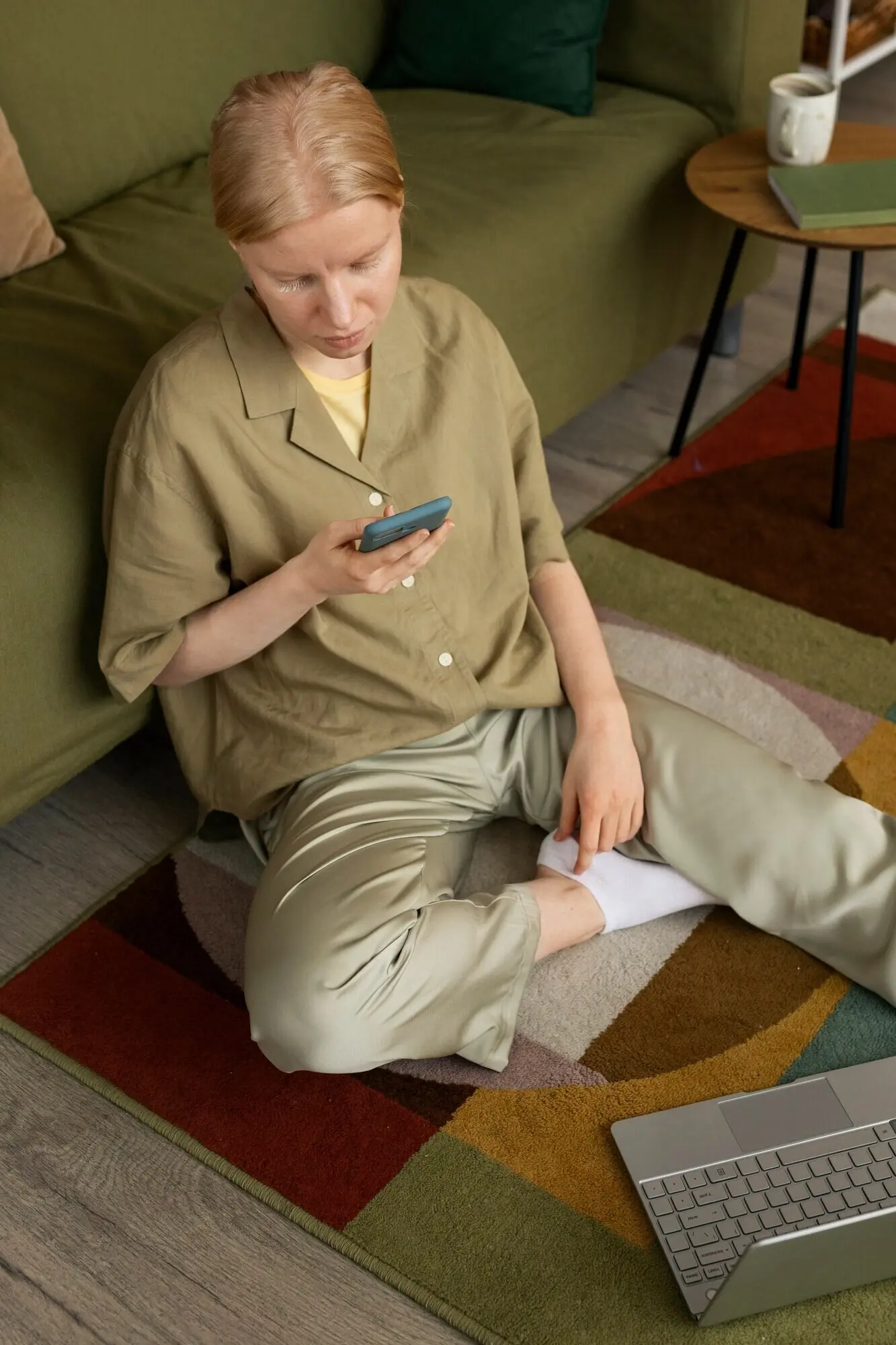 Ganzkörperaufnahme einer Frau mit Albinismus, die auf dem Boden sitzt.